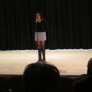 A student recites a poem on stage