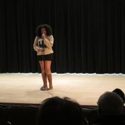 A student recites a poem on stage