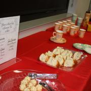 Tea cups and snack items on a red tablecloth.