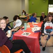 People sitting at a table drinking tea and crafting.