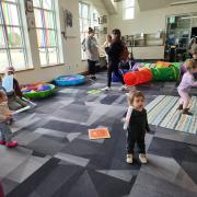 Babies and their caregivers dance around the Baby Rave room