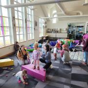 Babies and their caregivers dance around the Baby Rave room