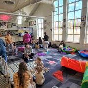 Babies and their caregivers dance around the Baby Rave room