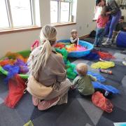 Babies and their caregivers dance around the Baby Rave room