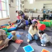 Babies and their caregivers dance around the Baby Rave room