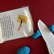 A photograph of the cutting foods station with play-doh and plastic knife.