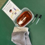 A photograph of the Wipe Up Messes station with red-dyed water and cloths.