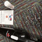 A photograph of the Vacuum up Messes station with paper pieces and a handheld vacuum on a rug.