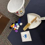 A photograph of the Pom Pom Sweep Up station with pom poms and a dust pan
