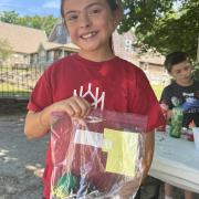 A  program participant smiles while holding a ziploc bag with tie dye shirt inside