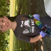A  program participant smiles while holding a ziploc bag with tie dye shirt inside