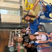 Participants smile in front of a local bakery