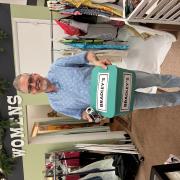 A smiling person holds a box labeled "Bradley's" inside a clothing store