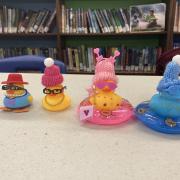 Four rubber ducks dressed up in small hats and other accessories.