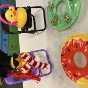 Two rubber duckies dressed up, sitting on small folding chairs with small pool floaties