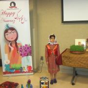 Child poses next to Nowruz banner