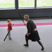 A child fights against an adult with a toy sword.