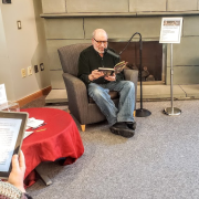 Photograph of reader sitting reading "A Christmas Carol" out loud