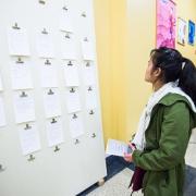Young woman reading poems on wall at opening reception