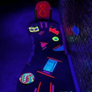 Photograph of Glow Golf hole lit up in neon colors under blacklights