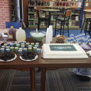 A cake, cookies and beverages set up on a table