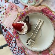 Photograph of a plate with a chocolate teacup and strawberry