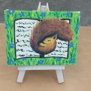 Photo of art canvas with painting of squirrel sleeping on book