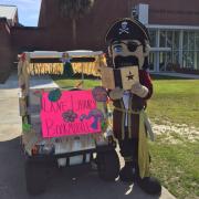 Pirate mascot reading a book next to golf cart