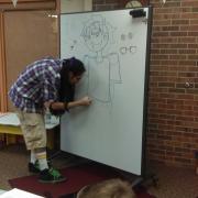 Artist demonstrating how to draw on a white board