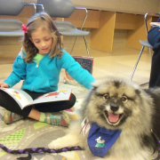 Young girl reading to fluffy dog
