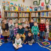 group of children sit in front of bookshelves 