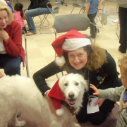 White dog wearing santa hat with owner and child