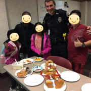 A police officer smiling with youth who made donut dioramas 