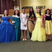 Twelve women dressed as princesses stand together and smile for the camera.