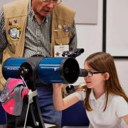 Young girl looks through a telescope