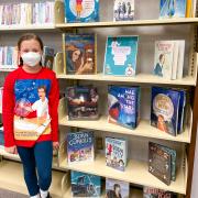 Photograph of Kid Librarian posing in front of display.