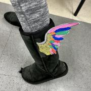 Photograph of black boots with rainbow wings.