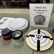 Photograph of an event station - Make an Olympian's Shield set up with paper plates, paint and other craft materials.
