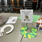 Photograph of an event station - Make a Laurel Wreath Crown set up with orange paper and Elmer's glue
