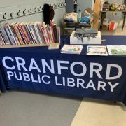Photograph of table covered with panel that reads Cranford Public Library. There are books on the table and a few handouts.