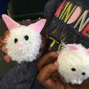 Child holding two pom-poms that look like bunnies