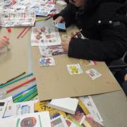  Photograph of kids working at a table with art supplies to create their Needs and Wants project