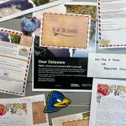 Photograph of pen pal program marketing in New Zealand: "Dear Delaware" postcard examples on a board. 
