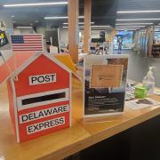 Photograph of pen pal post set up on a library desk. Post box "Delaware Express" with flags.