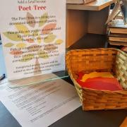 A basket of paper leaves with a sign that reads "add to our Poet-Tree" with instructions on how to add a poem.