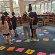A group of program participants play the game standing on colorful foam tiles.