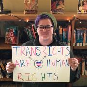 Person holding a sign that reads "Trans rights are human rights"
