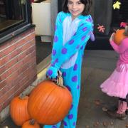 Girl in costume picks out her pumpkin