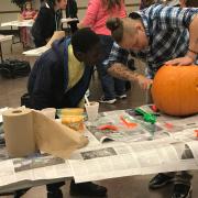 Two teens carving a pumpkin