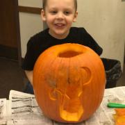 A child posing with his carved pumpkin